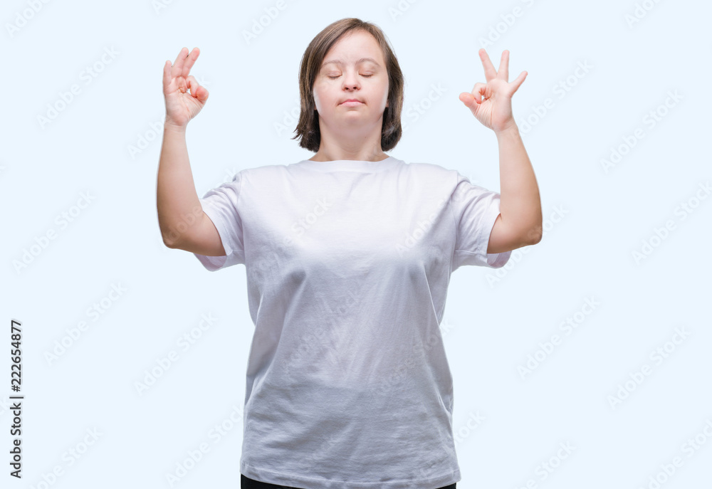 Young adult woman with down syndrome over isolated background relax and smiling with eyes closed doing meditation gesture with fingers. Yoga concept.