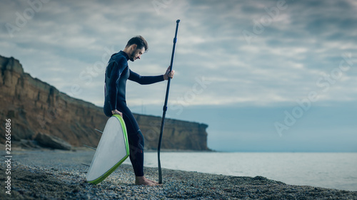 Photography Portrait of a young male surfer in a wetsuit on the beach.
