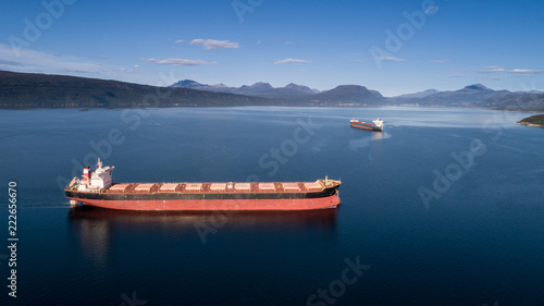 Aerial shot of a cargo ship on the open sea with other ship and mountains in the background, Narvik, Norway