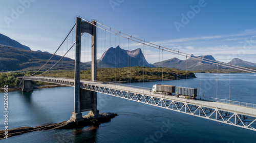 Aerial shot of a bridge over Efjord with a truck and mountain Stortinden in the background, Ballangen, Norway