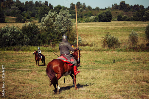 Knight tournament. Medieval armored equestrian soldiers with lances on horses. Riders are in the field