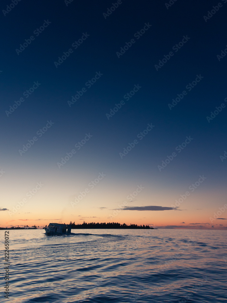 Fototapeta premium Moon rises over beautiful Maldivian sunset with boat