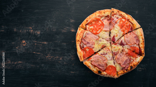 Pizza with bacon, tomatoes and onion. Italian cuisine. On a wooden background. Free space for text. Top view.