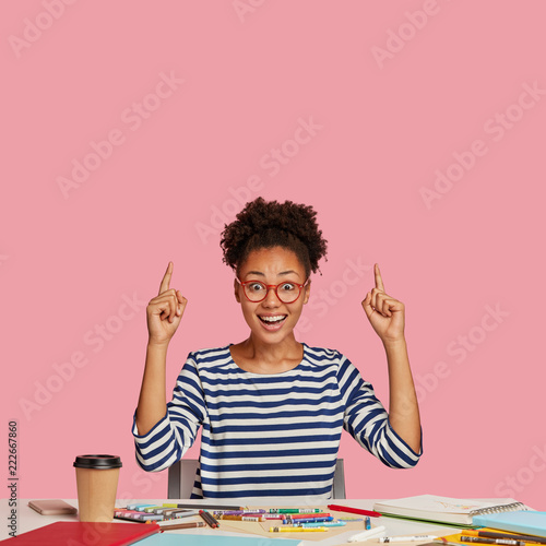 Quadro em tela Vertical shot of overjoyed illustrator in casual clothes, works from home, uses