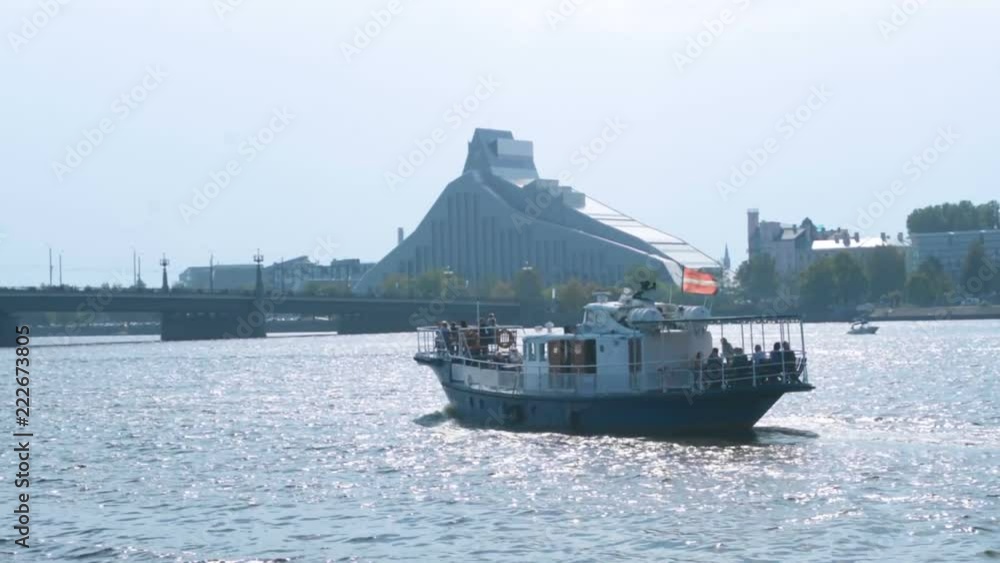 Motor boat cruise ship on the river carrying tourists, small river ferry weekend summer tourist attraction in Riga Motor boat cruise ship on the river carrying tourists, small river ferry weekend summer tourist attraction in Riga