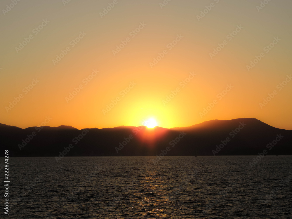 Naklejka premium Sunset between the mountains by the sea