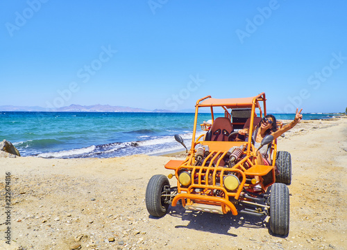 A happy girl driving a Buggy on a dune of beach with the Aegean sea in background. Greek island of Kos. South Aegean region, Greece.