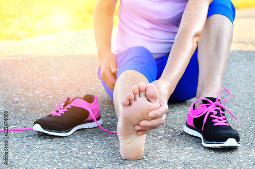 Running injury leg accident- sport woman runner hurting holding painful sprained ankle in pain.Athlete woman has ankle injury  sprained ankle during running training.Space for text