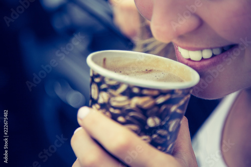 Junge fröhliche Frau trinkt Kaffee aus einem Becher, weiße Zähne photo