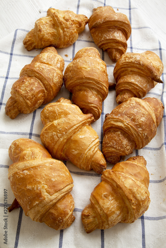 Fresh croissants on cloth on white wooden background, high angle view. Closeup. Fresh croissants on cloth on white wooden background, high angle view. Closeup.