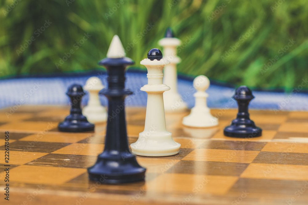 soft focus creative close foreshortening chess black and white figures on wooden classic yellow desk with quadratic marking on unfocused background soft focus creative close foreshortening chess black and white figures on wooden classic yellow desk with quadratic marking on unfocused background