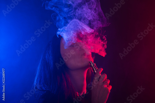 Young woman in black t-shirt vaping in red and blue neon light