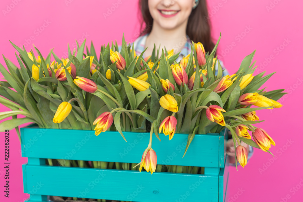 Close up of bright wooden box with yellow tulips in pink studio. Close up of bright wooden box with yellow tulips in pink studio.