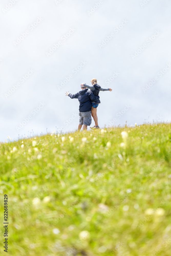 A young couple stand in a mountain meadow