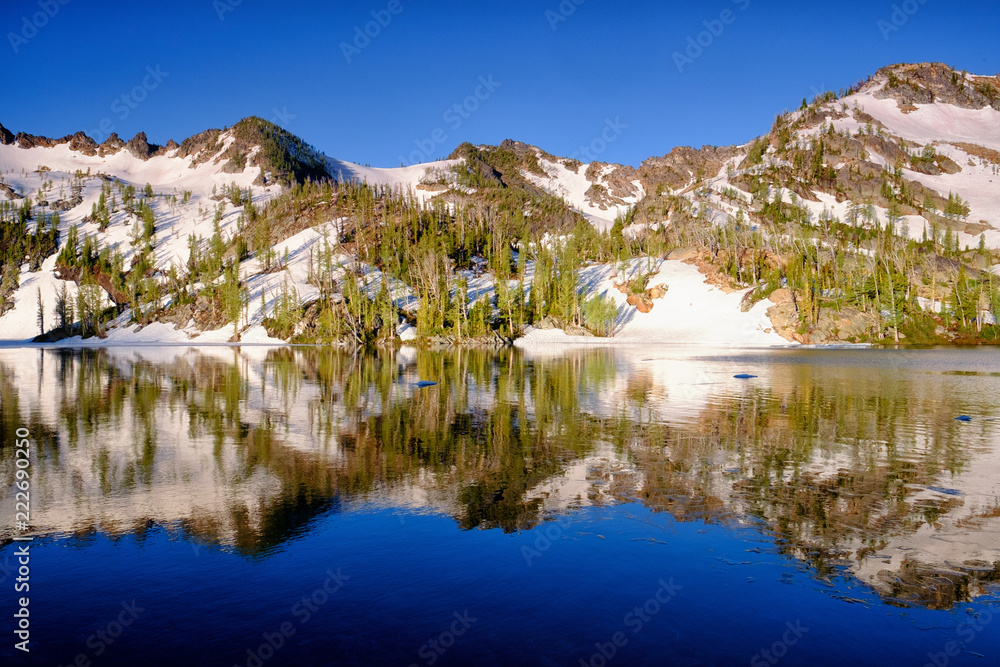 A snowy cirque reflects in a mountain lake