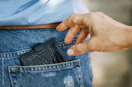 фотографія Theft of a purse from a jeans pocket in the daytime on the street, close-up