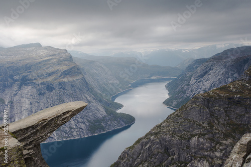 View of Trolltunga cliff and lake between mountains, picturesque landscape, beauty in nature, paradise on Earth, sunny day, Odda, Norway.