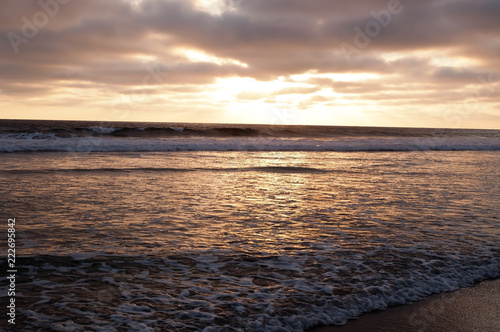 A southern California  USA sunset in summer with the fading sunlight shining over the shore of the Pacific ocean