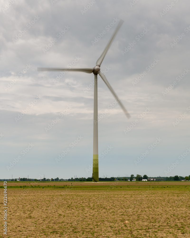 Fototapeta premium Wind Turbine In An Empty Field Under A Cloudy Grey Sky