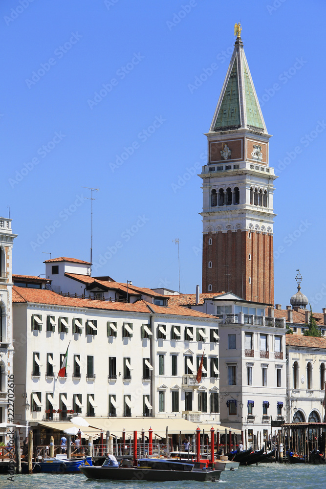 Venice canal, boat traffic, mooring posts and St Mark's Campanile, bell tower, in the background - famous place, Veneto, Italy; attraction, sightseeing, vacations, travel, romance, tourism.