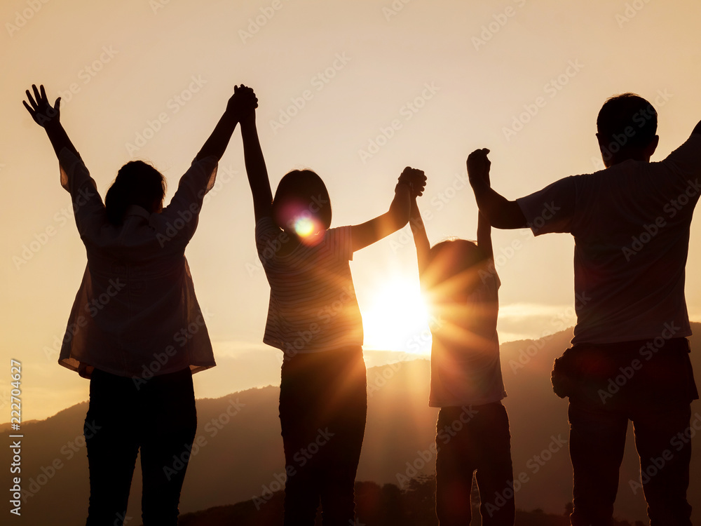 Silhouette of happy family standing with raised hands on the mountain at the sunset time. Silhouette of happy family standing with raised hands on the mountain at the sunset time.