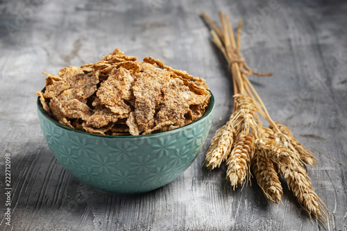 Photos Multigrain wholewheat healthy cereals in ceramic bowl and golden wheat ears on gray background