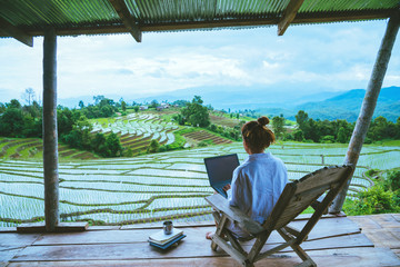 Asian woman travel nature. Travel relax. sit reading book the balcony of the resort. View of the field on the Moutain in summer. Thailand