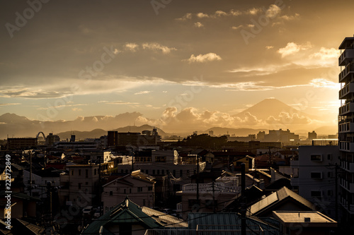 Bright sunset illuminating a small city with mount Fuji looming in the background