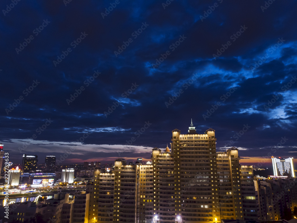 Beautiful cityscape of Minsk at night. Aerial top view of modern apartment buildings under illumination with dramatic sky