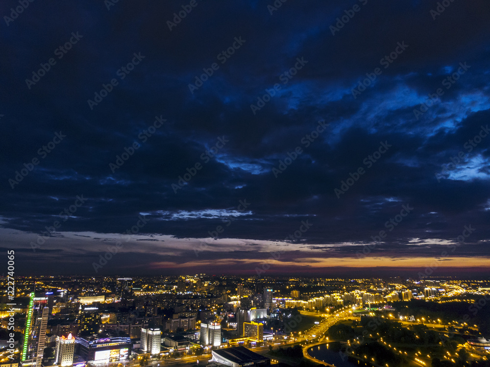 Night aerial view of downtown. Urban architectures with illumination under dramatic sky