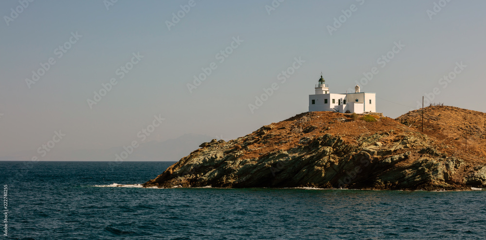 Lighthouse and agios Nikolaos church on rocky land. Kea,Tzia island, Greece. Sky background, banner.