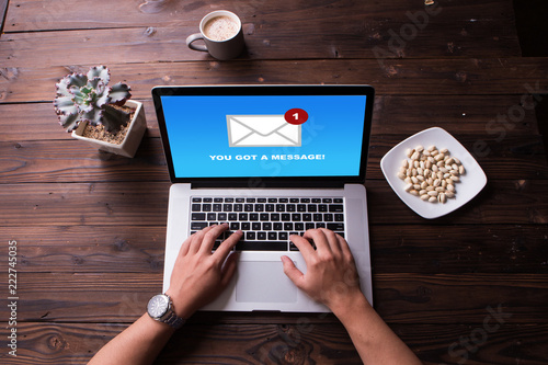 Top view of man hands working on laptop and got a mail message with wooden desk background photo