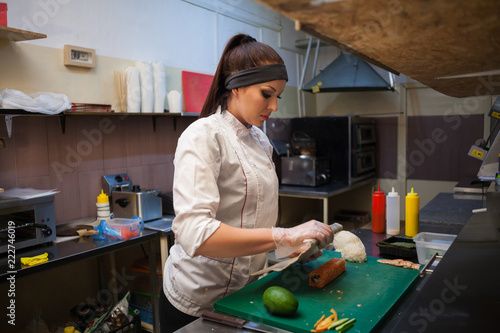 woman Cook prepares sushi on restaurant kitchen