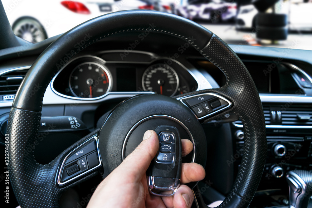 Man's hand holding a wireless car key in black leather interior. Modern Car interior details. Car detailing. Car inside. Car detailing