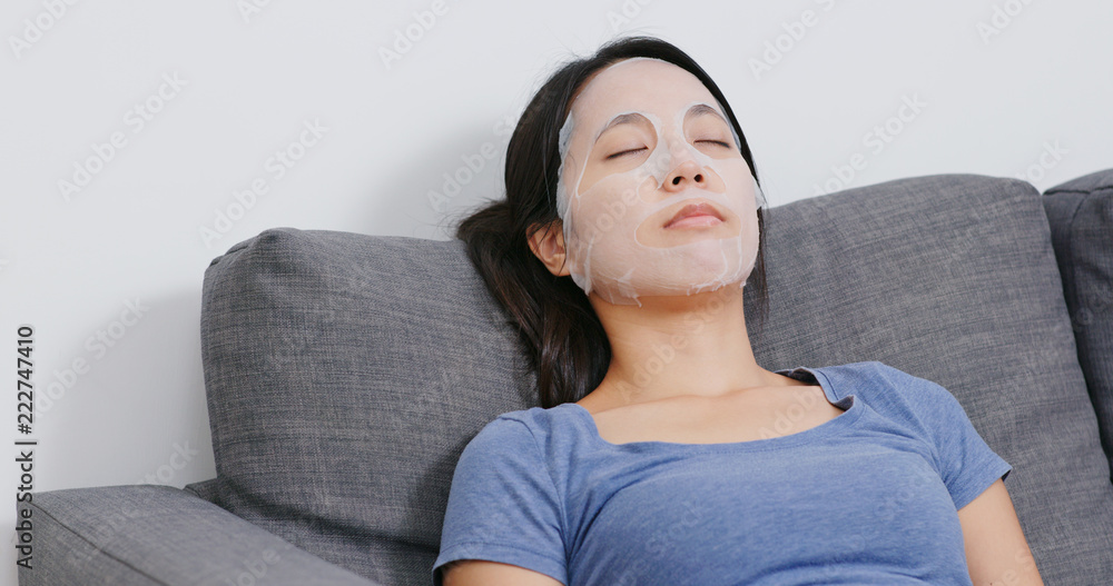 Woman apply face mask on face and lying on sofa Woman apply face mask on face and lying on sofa