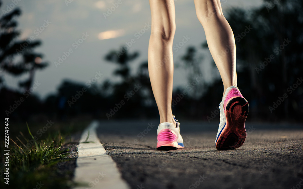 Runner feet running on running road closeup on shoe. woman fitness sunrise jog concept...