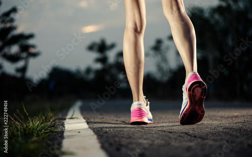 Runner feet running on running road closeup on shoe. woman fitness sunrise jog concept...