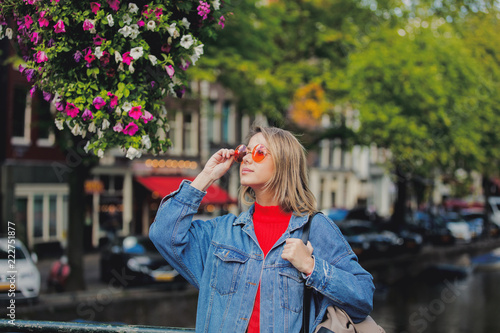 Photography Young girl in red sweater and orange sunglasses with backpack at bridge in Amsterdam street