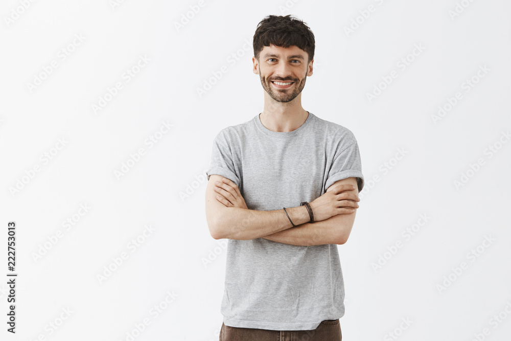 Creative and stylish young entrepreneur being satisfied with growth of company, standing over gray background with hands crossed on chest and broad pleased smile, having great time Creative and stylish young entrepreneur being satisfied with growth of company, standing over gray background with hands crossed on chest and broad pleased smile, having great time