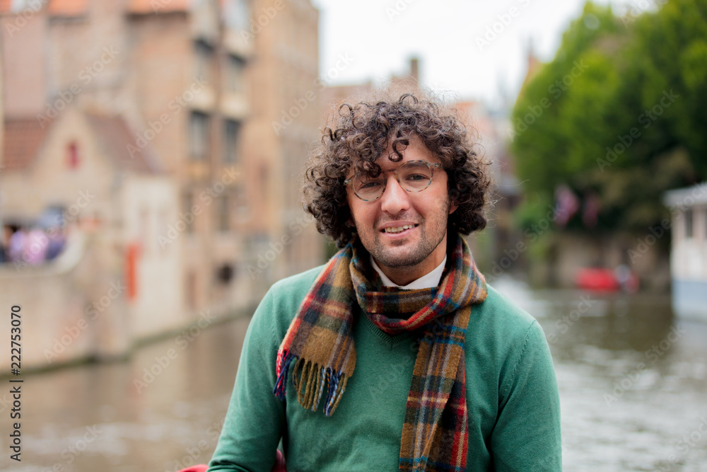 Young man in sweater and scarf looking at camera. Bruges, Belgium