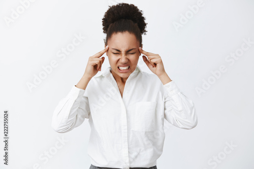 Thinking with all brain power. Portrait of intense focused serious-looking woman with dark skin in white-collar shirt, clenching teeth and raising tension while trying concentrate and made up plan