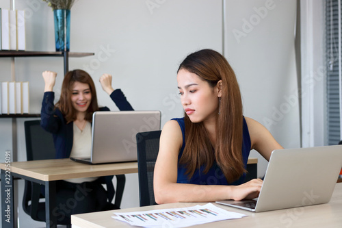 Fototapet Angry envious Asian business woman looking successful competitor colleague in office