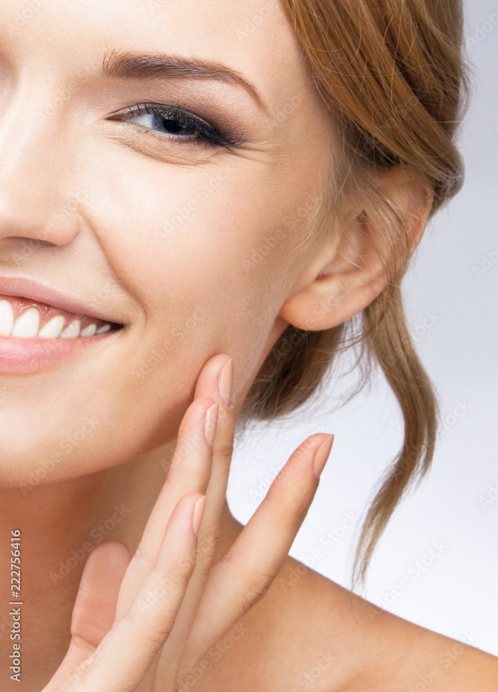 Woman touching skin or applying cream, on grey Woman touching skin or applying cream, on grey