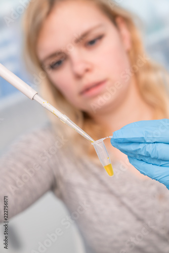Close up of Young female scientist working in genetics laboratory with pipette in white biological sample