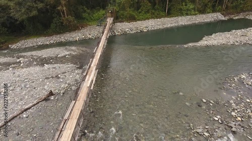 Flying over a rickety suspension footbridge crossing the Rio Cosanga on the Amazonian slopes of the Andes in Ecuador. photo