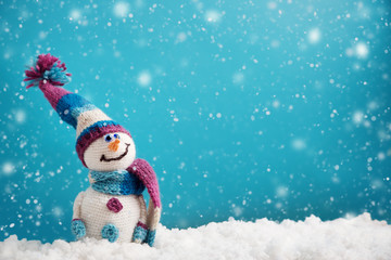 little knitted snowmans on soft snow on blue background
