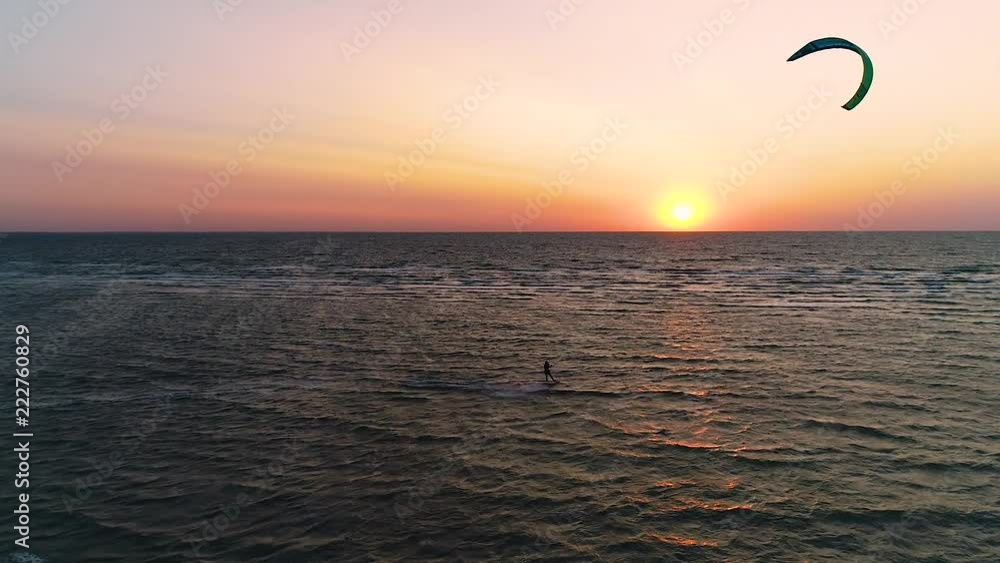 Tricks on Kitesurf. Orange sunset in the sea, a couple of people engaged in kitesurfing. Aerial shooting Tricks on Kitesurf. Orange sunset in the sea, a couple of people engaged in kitesurfing. Aerial shooting