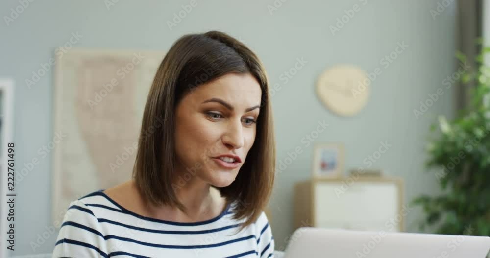Close up of the smiled Caucasian young woman having videochat on the laptop computer and talking cheerfully at home. Close up of the smiled Caucasian young woman having videochat on the laptop computer and talking cheerfully at home.