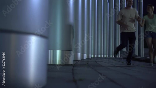 Playful girl running away from guy, flirting, hide-and-seek game between columns