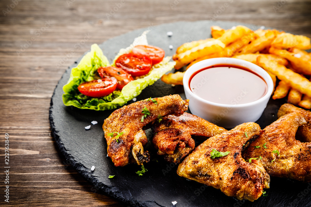 Grilled chicken wings, chips and vegetables Grilled chicken wings, chips and vegetables
